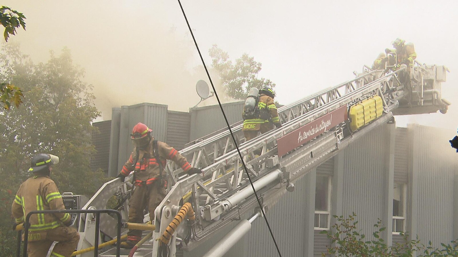 Quatre pompiers sur une échelle.