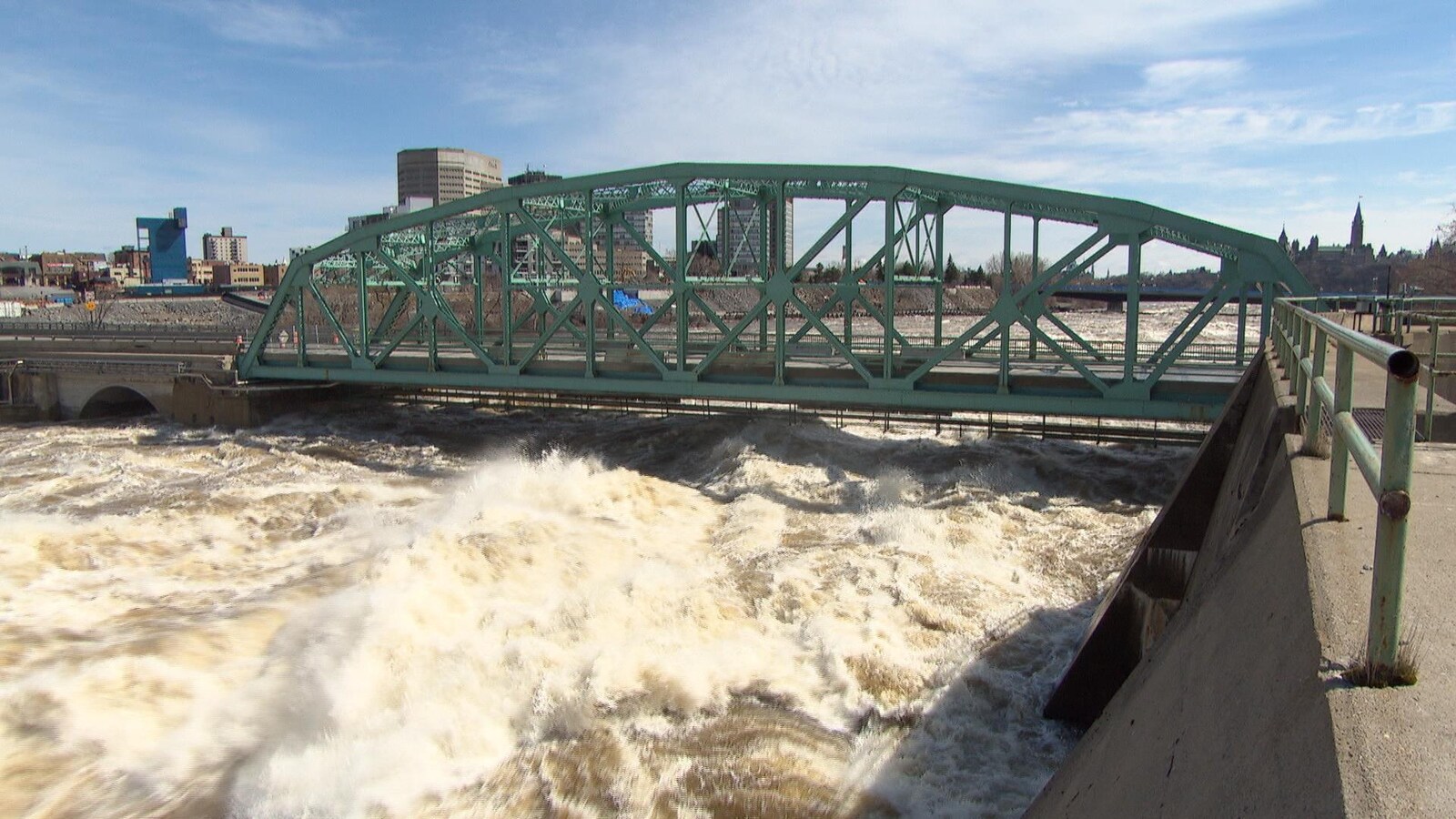 L'eau tumultueuse atteint presque le tablier du pont.