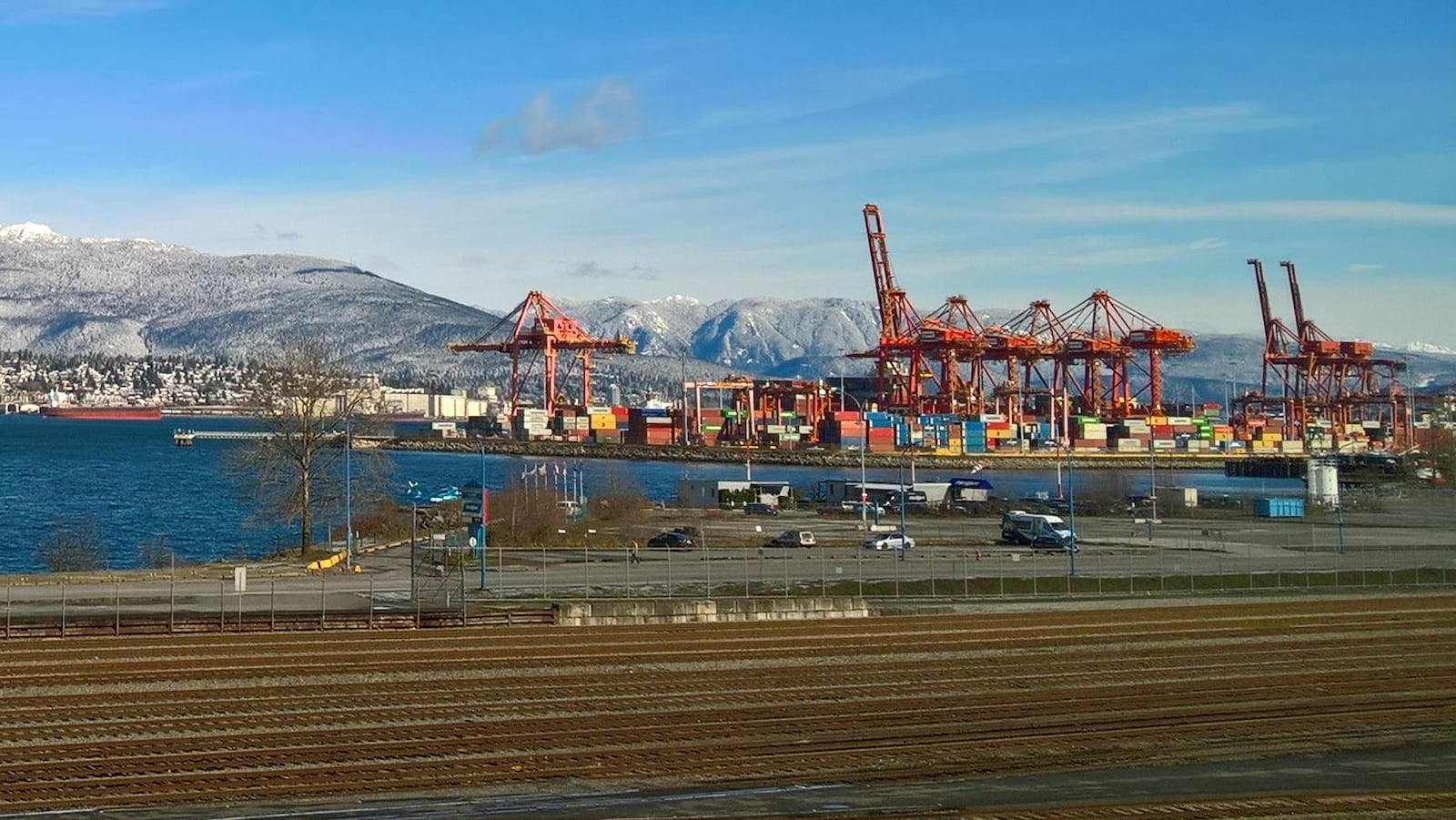 Des chemins de fer longent le port de Vancouver et ses conteneurs assemblés sous des grues.