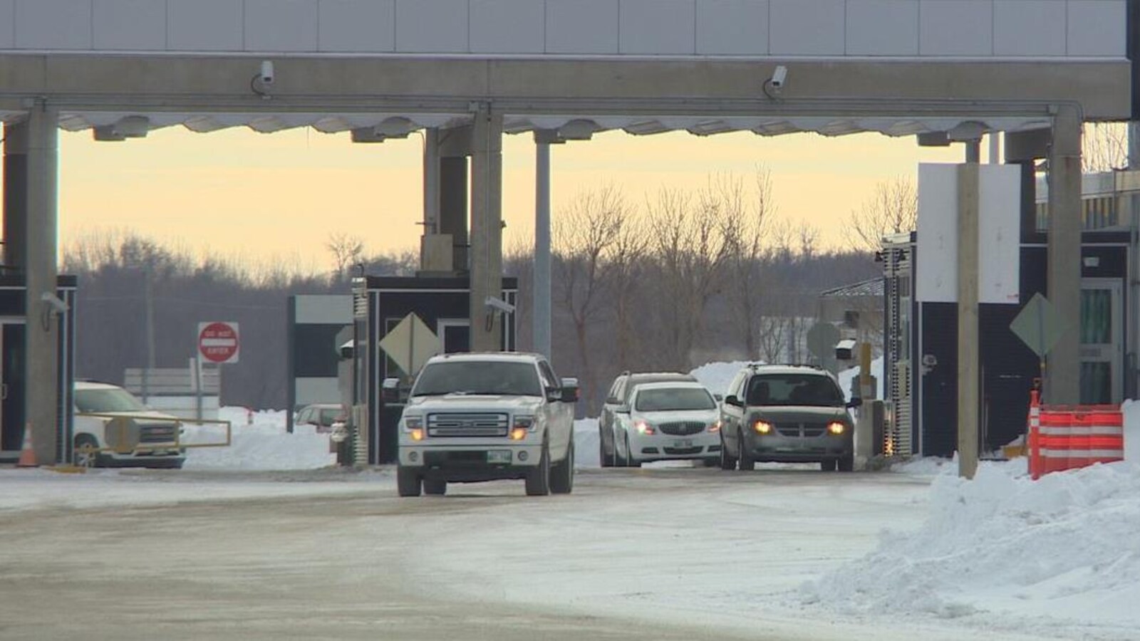 Des véhicules sont au poste frontalier d'Emerson avec de la neige accumulée au bord de la route