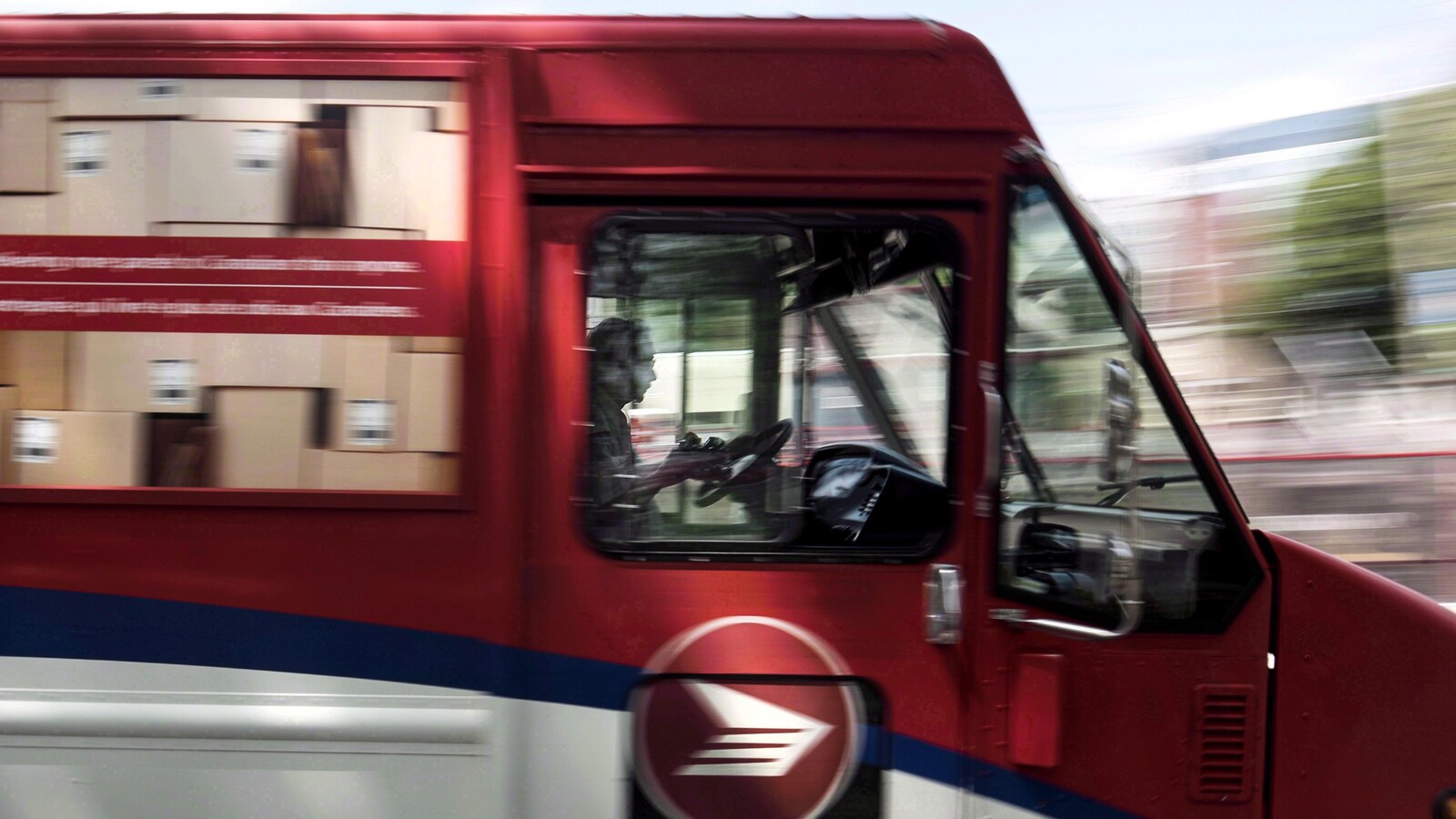 Un employé de Postes Canada conduit un camion de la société.