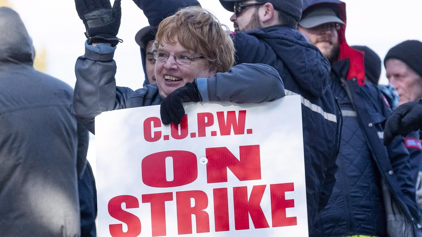 Une femme tient une affiche sur laquelle est écrit en rouge : « En grève ».
