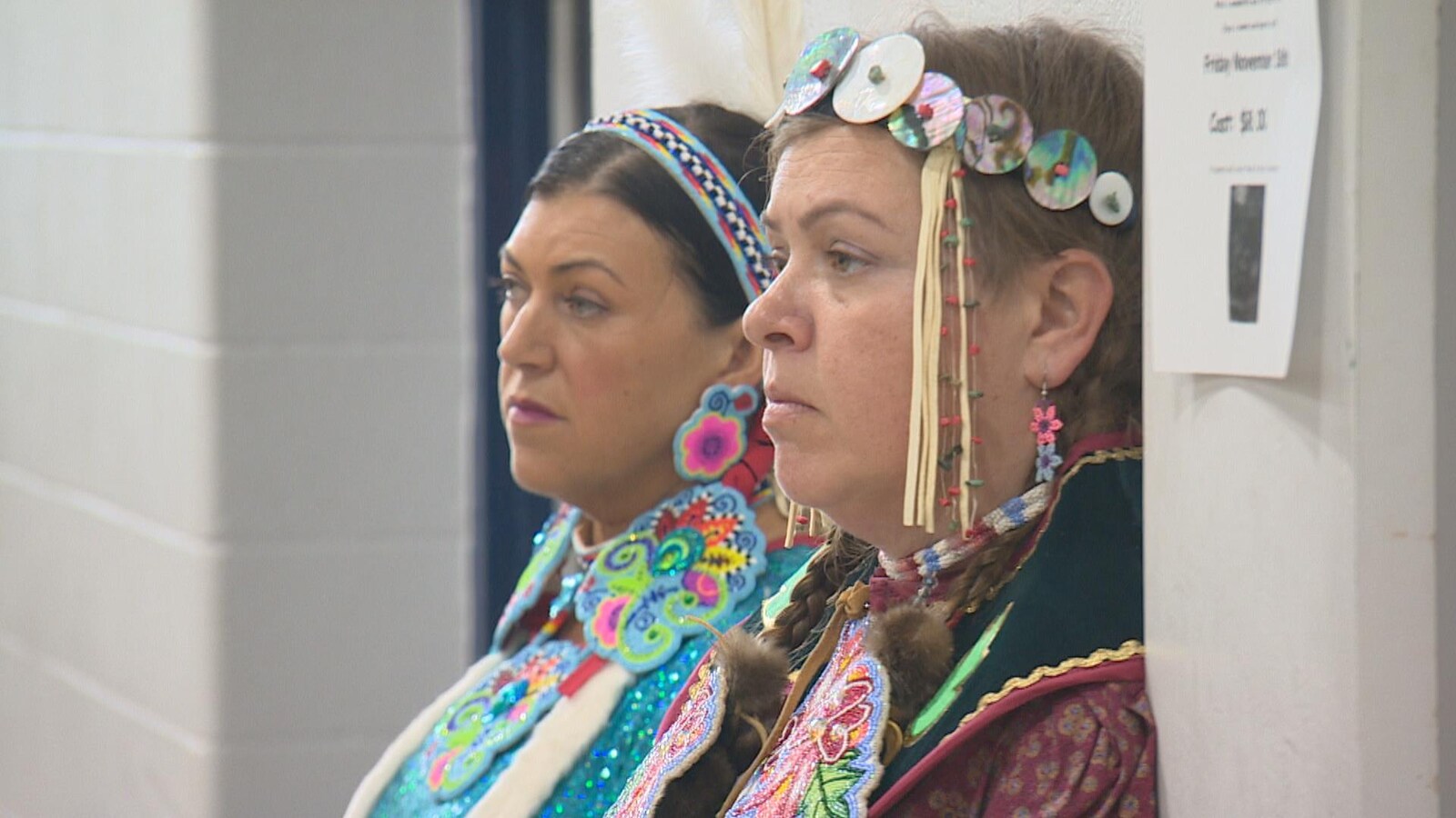 Gros plan des visages de deux femmes accotées sur le mur, vêtues traditionnellement..