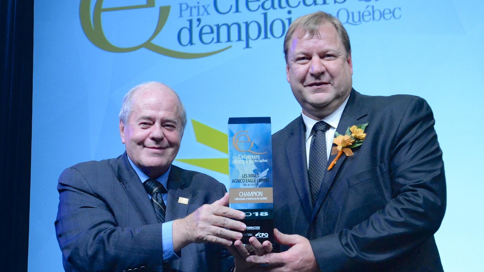 Deux hommes posent pour la caméra lors d'une remise de trophée.