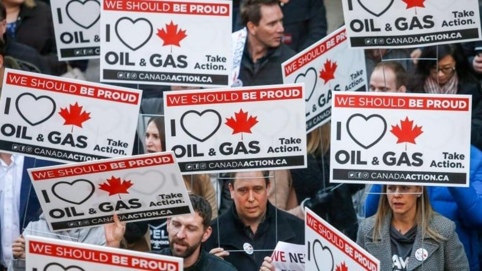 Une foule de manifestants brandit des pancartes indiquant en anglais: « we should be proud » et « I love oil and gas ».