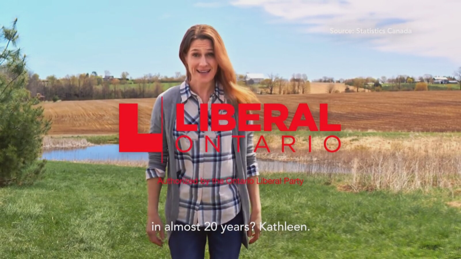 Image de la publicité télévisée. Une femme en jeans et chemise à carreaux marche dans un champ en région rurale.