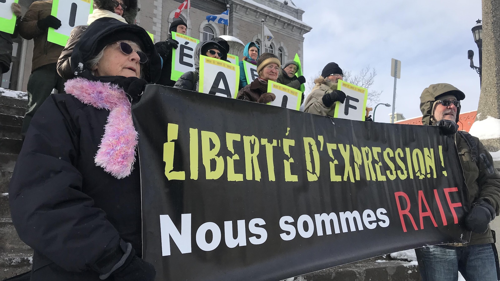 Des gens tiennent une banderole devant l'hôtel de Sherbrooke pour dénoncer l'emprisonnement de du blogueur.