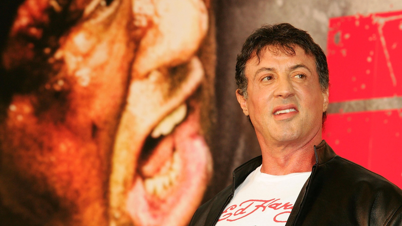 L'acteur Sylvester Stallone pose devant une affiche du film Rambo