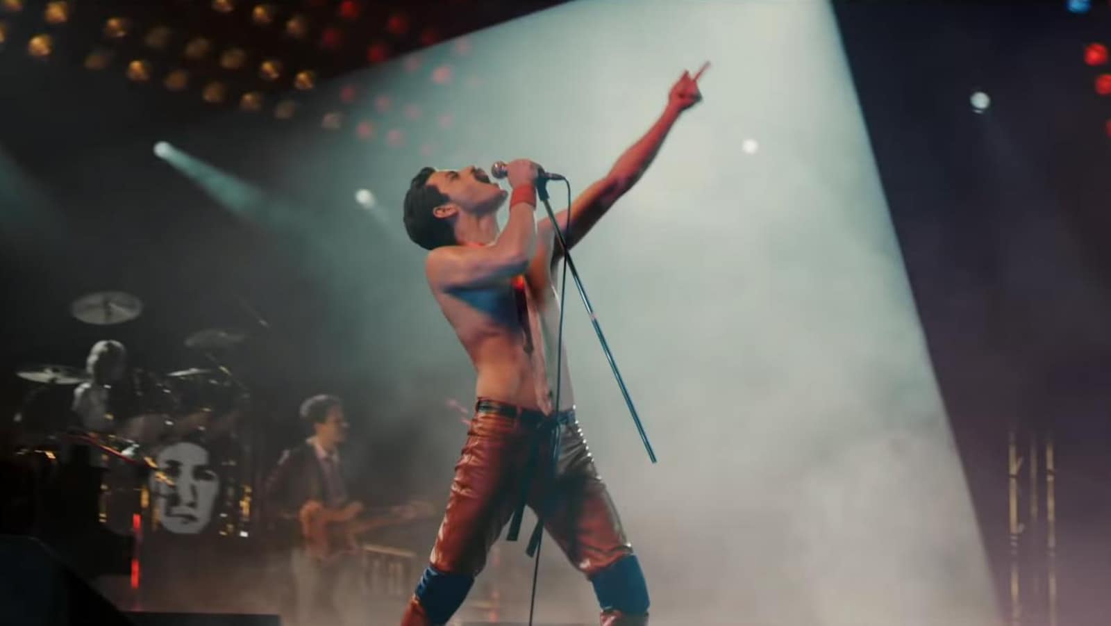 Rami Malek, torse nu, lève le bras en l'air, pendant qu'il est en train de chanter sur une scène dans le film «Bohemian Rhapsody».