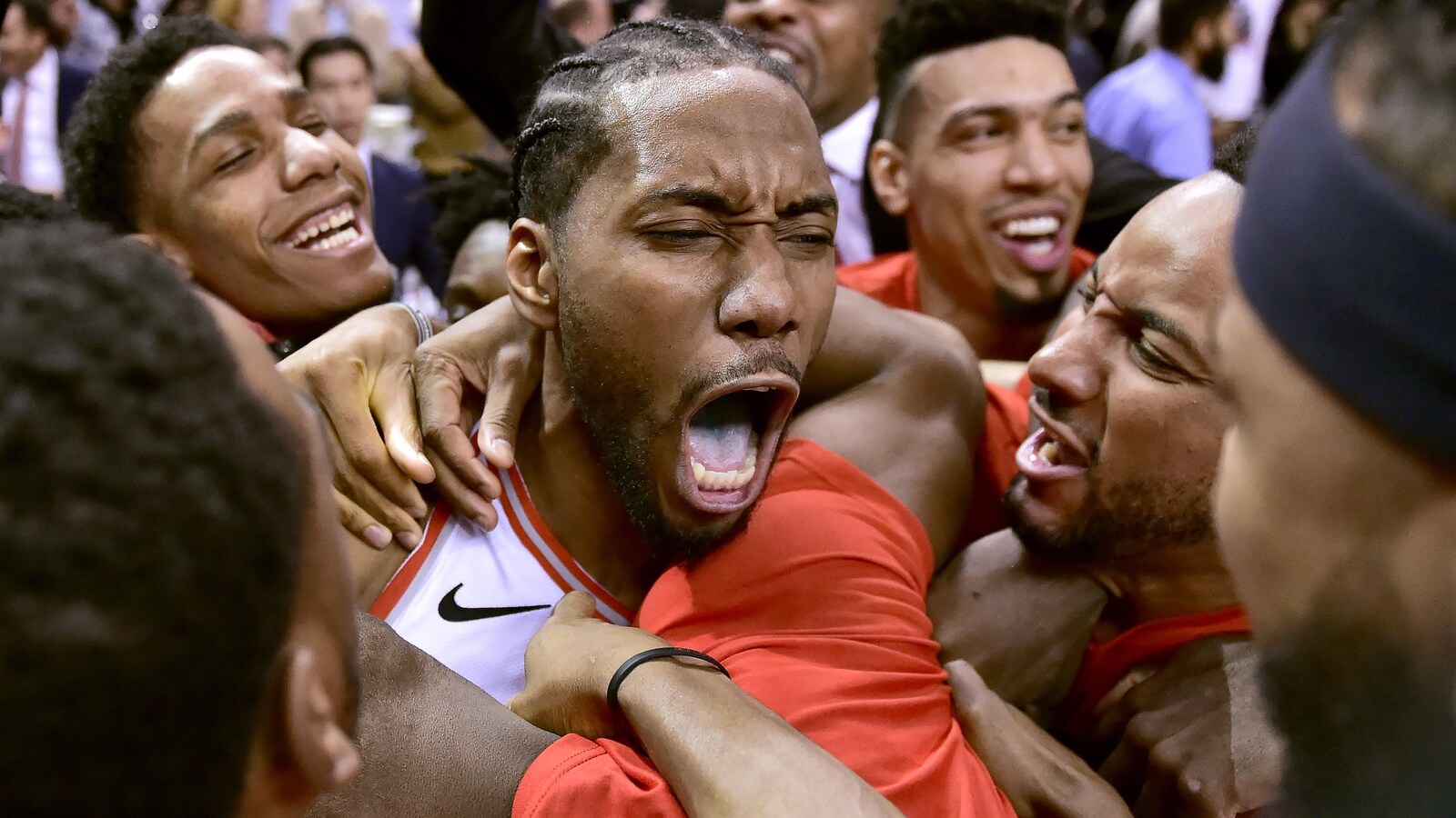 Photo d'un homme la bouche ouverte qui crie sa victoire entouré de ses coéquipiers.