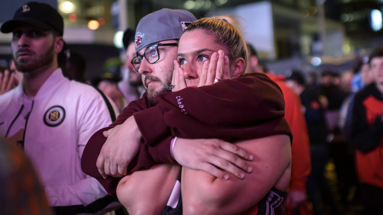 Un homme serre une femme dans ses bras en regardant le match.