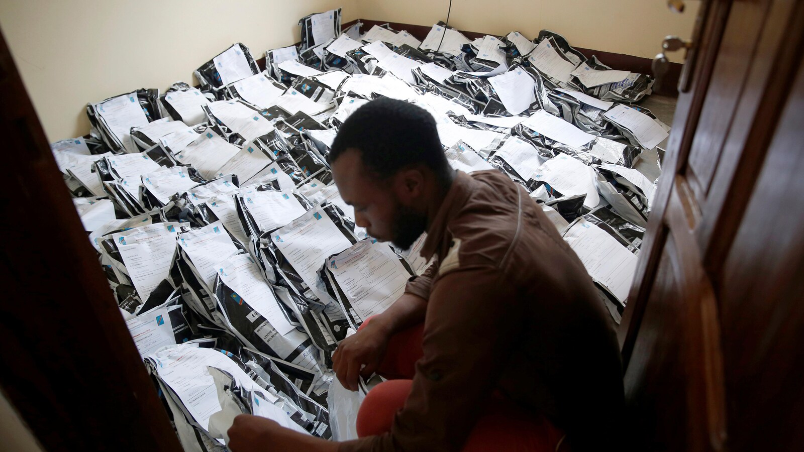 Un homme dans un local sont le sol est rempli de matériel électoral
