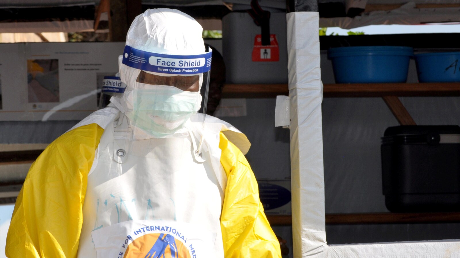 Un travailleur médical porte un uniforme de protection et un masque.