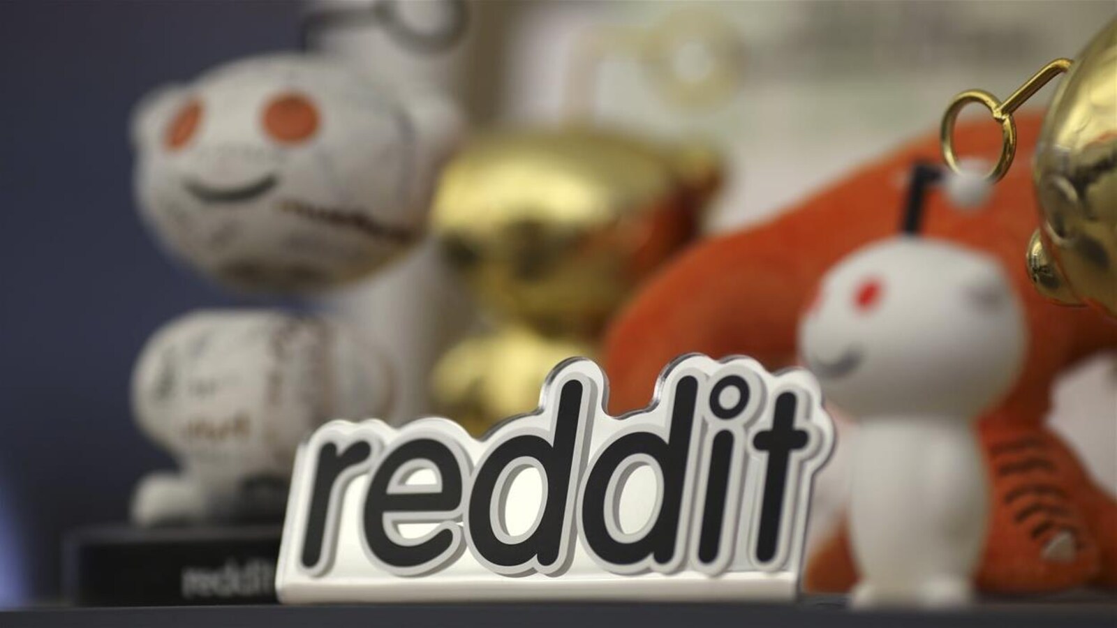 Le logo de Reddit est posé devant des petites figurines à l'image de l'entreprise
