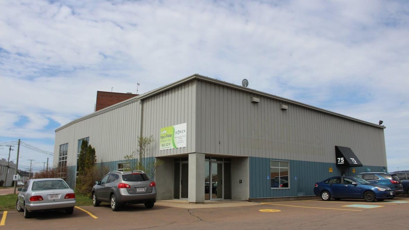 Un immeuble entouré d'un stationnement avec quelques voitures qui y sont garées.