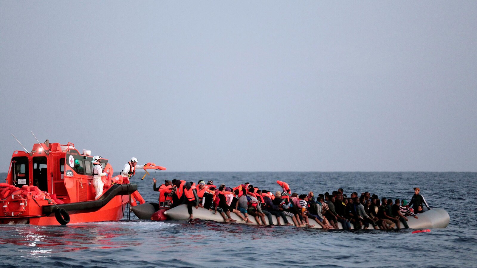 Des dizaines de migrants sur une embarcation gonflable rescapés en mer par la Croix-Rouge.