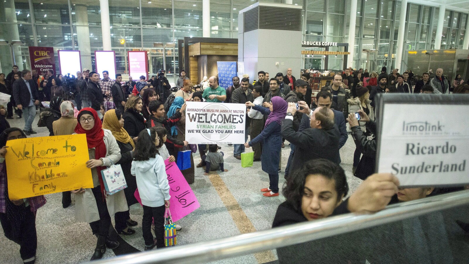Des groupes de parrainage attendent des familles syriennes à l'aéroport de Toronto en décembre 2015.