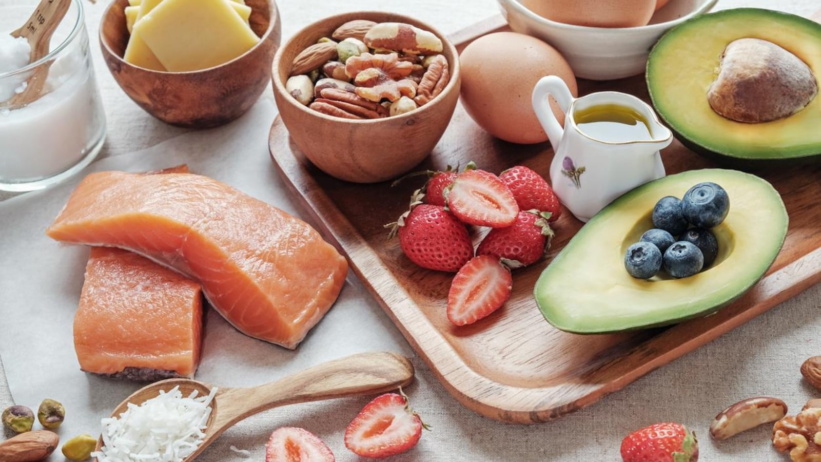 De l'avocat, des noix, des oeufs, du saumon et du fromage sont présentés sur un plateau en bois.