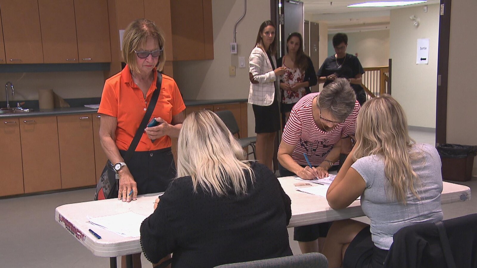 Des citoyennes signent le registre pendant que d'autres attendent.