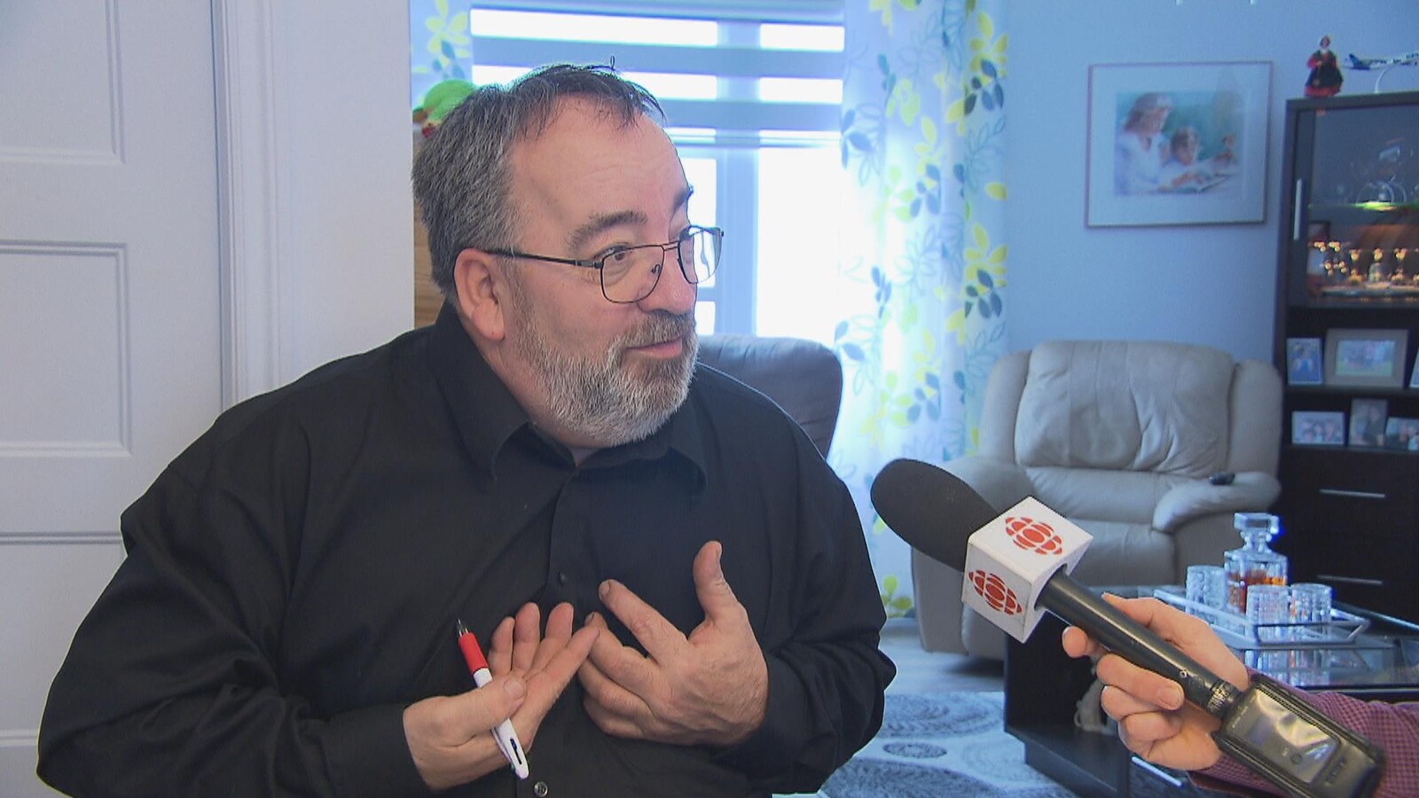 Un homme accorde une entrevue à Radio-Canada. Il est dans sa maison.