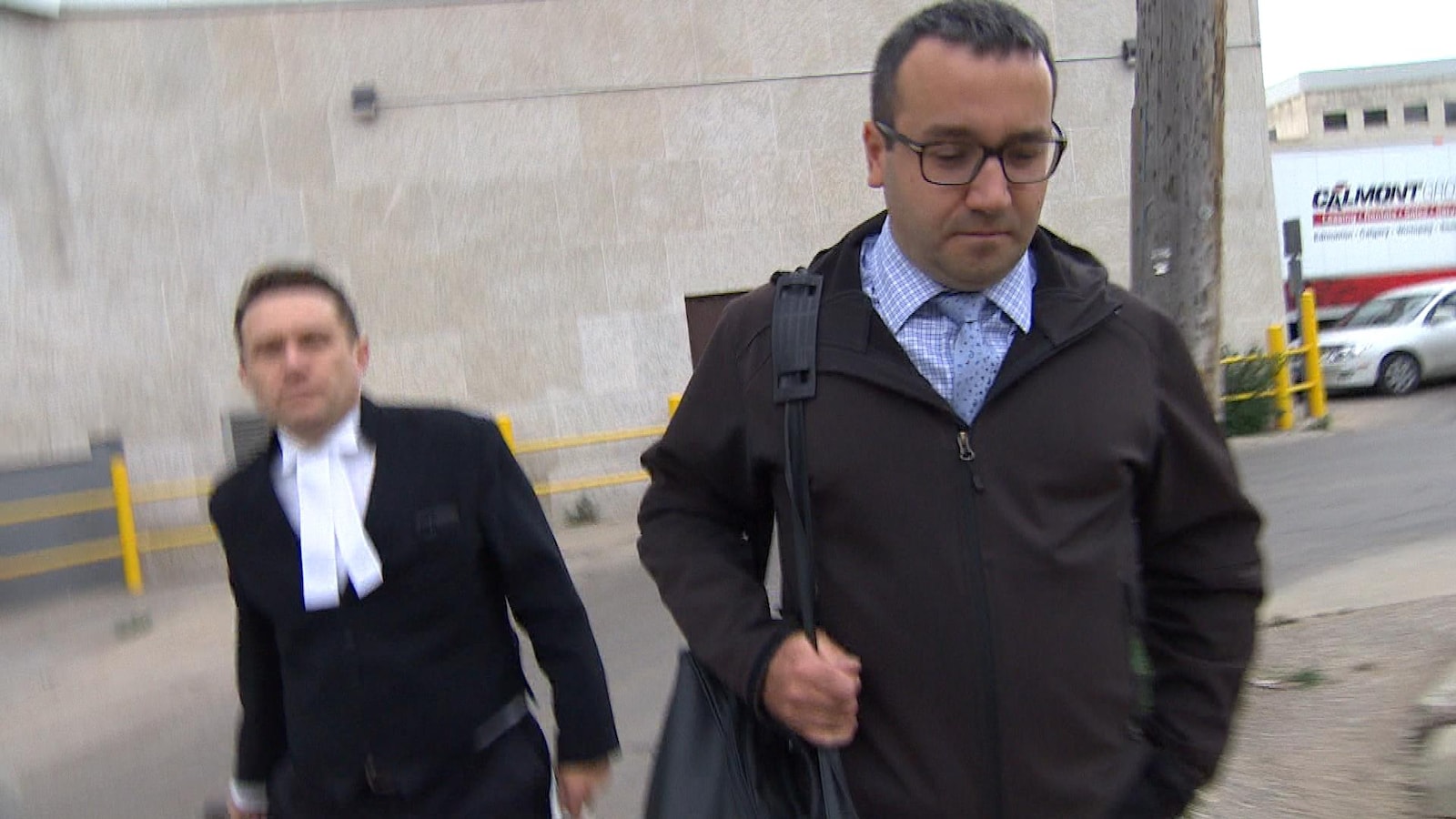 Rémi Dallaire marche, en regardant par terre, avec son avocat à sa gauche.