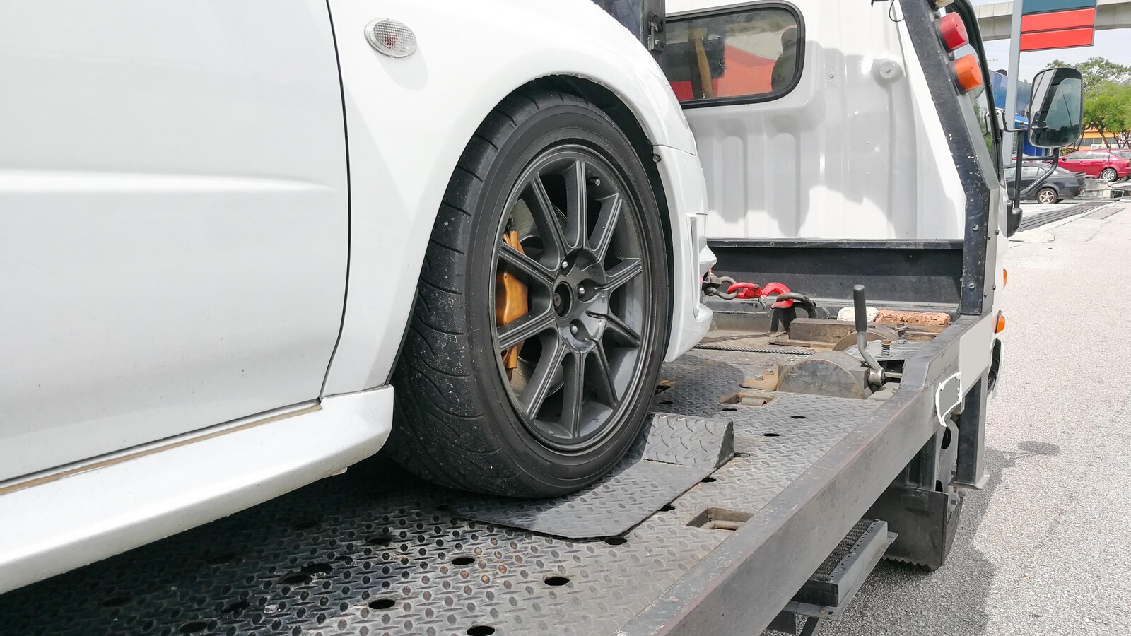 Une voiture blanche est transportée par une remorqueuse.
