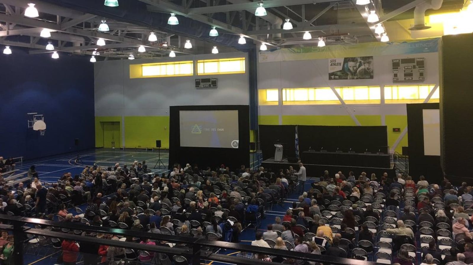 Des centaines de personnes assises dans un gymnase.