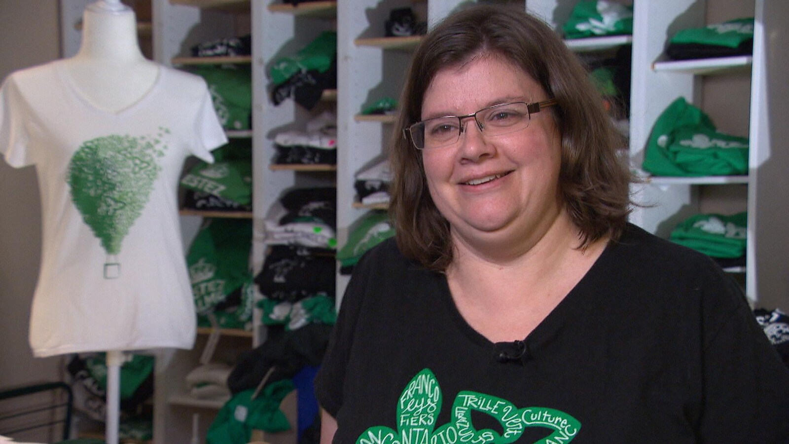 Renée O'Neill pose devant des étagères remplies de t-shirts.