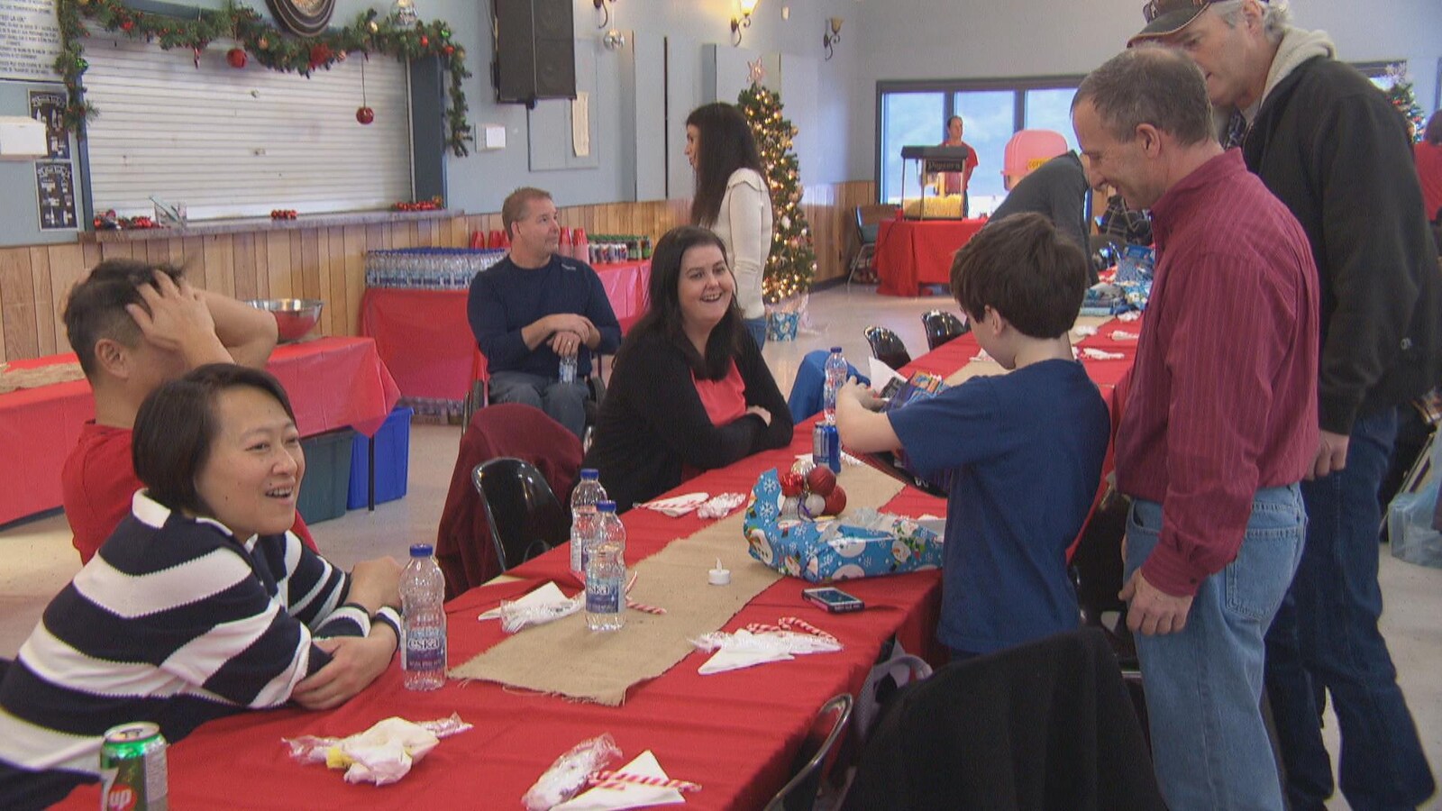 Des gens autour d'une table dans une salle décorée pour le temps des Fêtes.