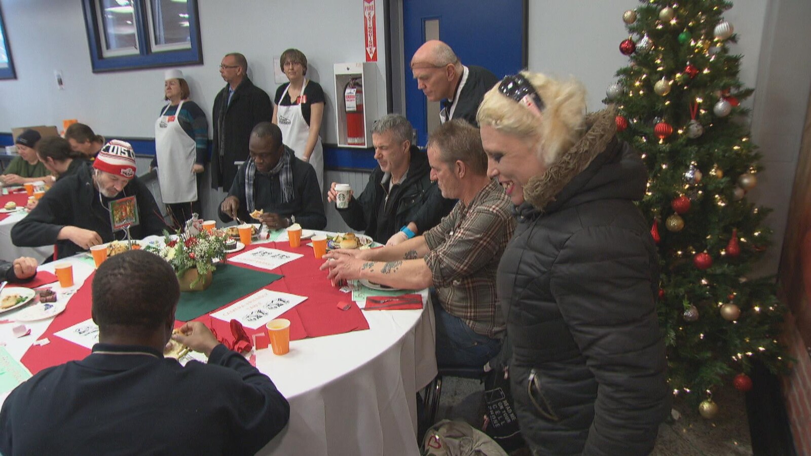 Des gens en train de manger alors qu'ils sont assis à une table dans un local de la Mission d'Ottawa.