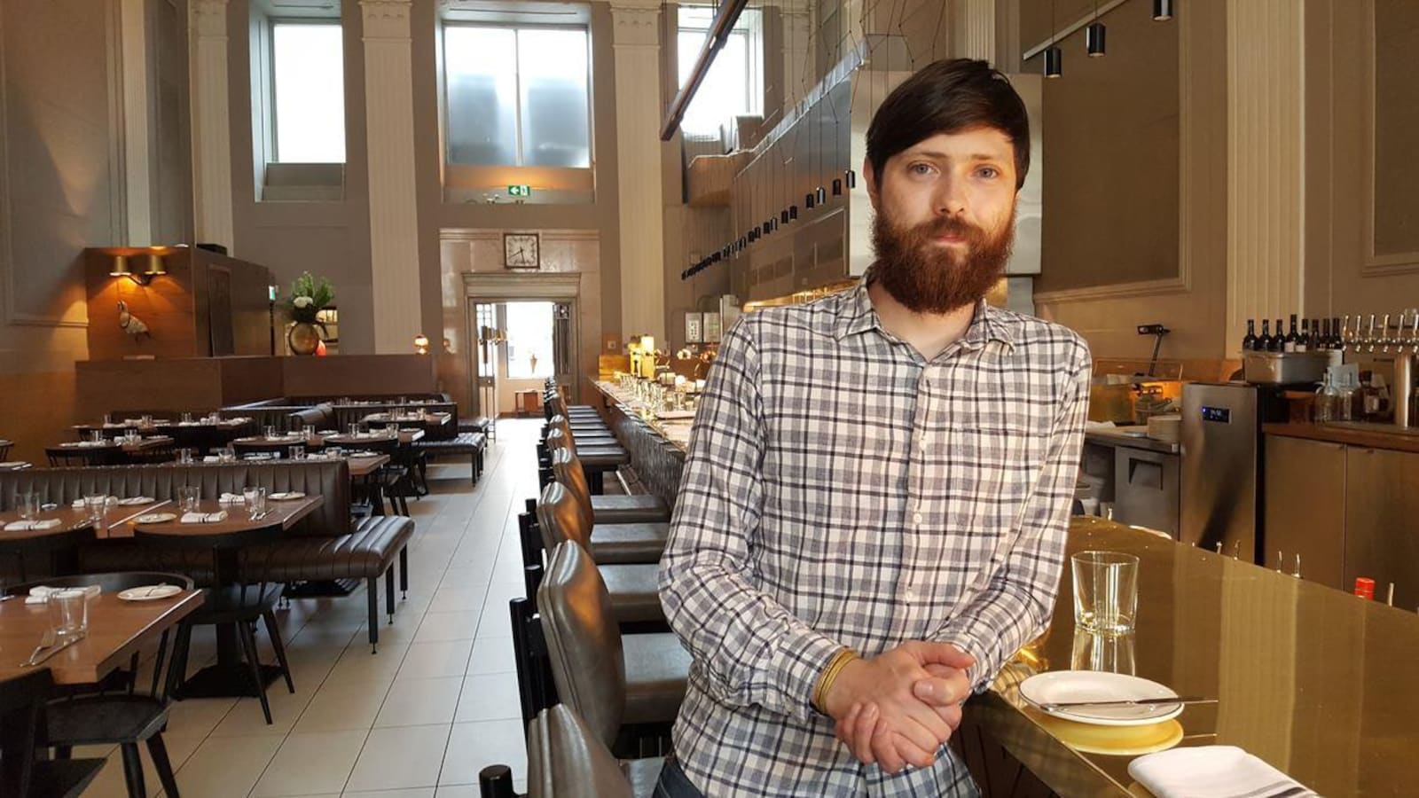 Un homme dans un restaurant, le coude posé sur une table.