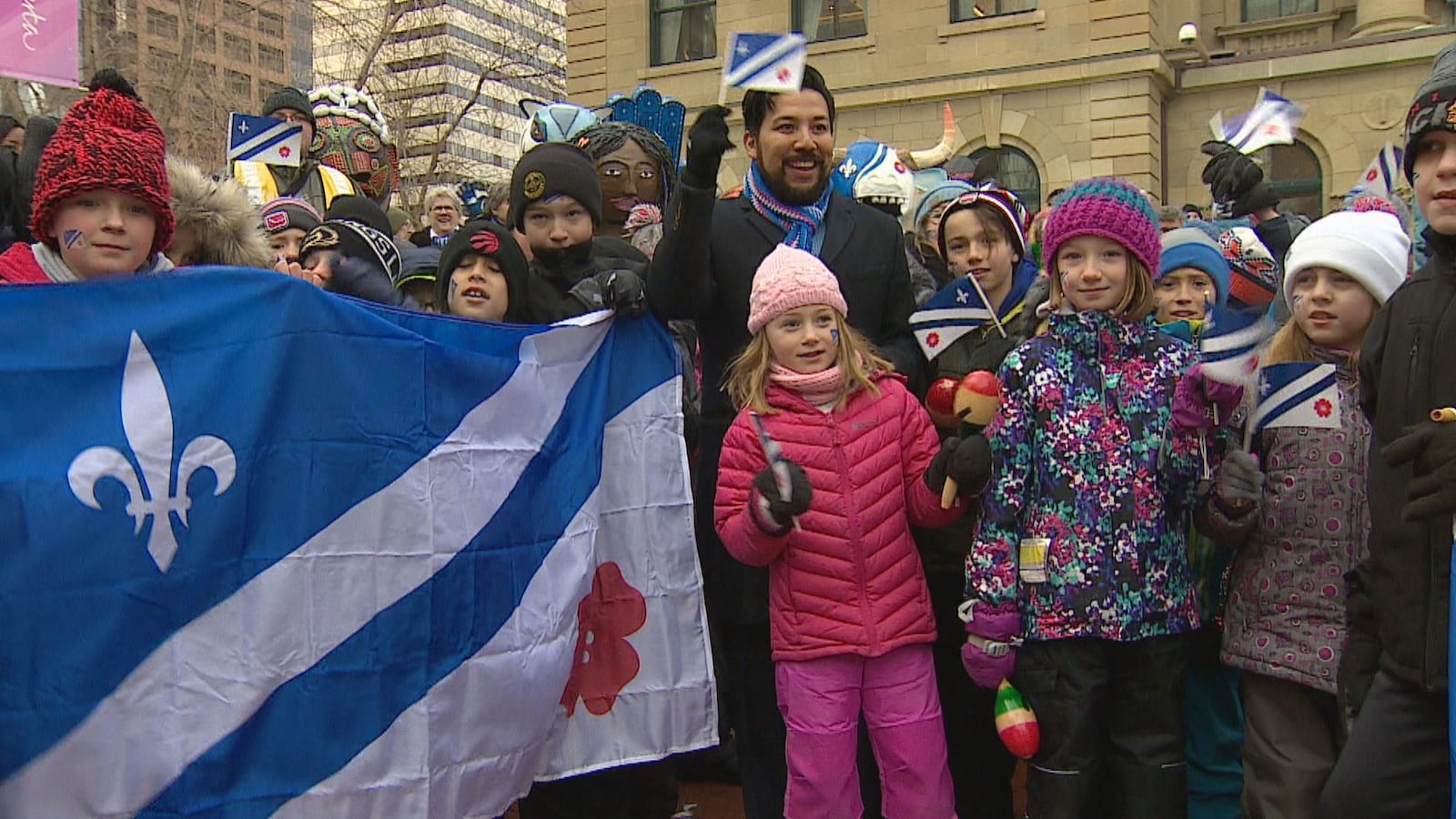 Un drapeau franco-albertain en premier plan et des enfants tenant des petits drapeaux. Les Francophones de l'Alberta ont franchi une nouvelle étape de leur reconnaissance en mars lorsque le ministre responsable du Secrétariat francophone Ricardo Miranda (au centre) a déclaré le mois de mars, Mois de la francophonie en Alberta.