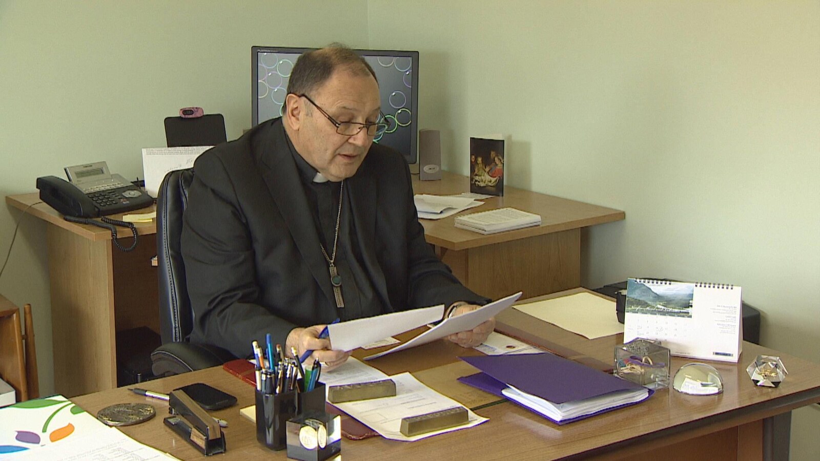 L'évêque Richard Grecco consulte des documents à son bureau.