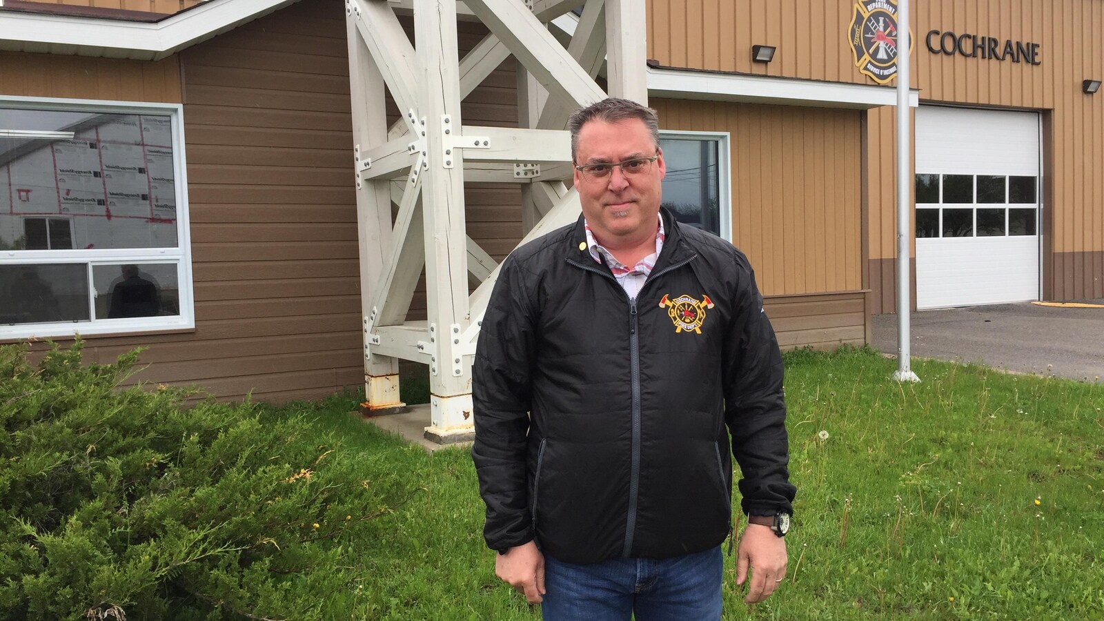 Un homme posant devant la caserne de pompiers de Cochrane.