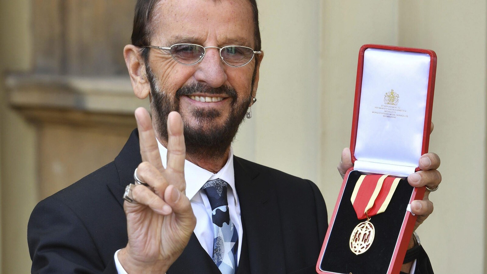 Ringo Starr tenant une médaille.