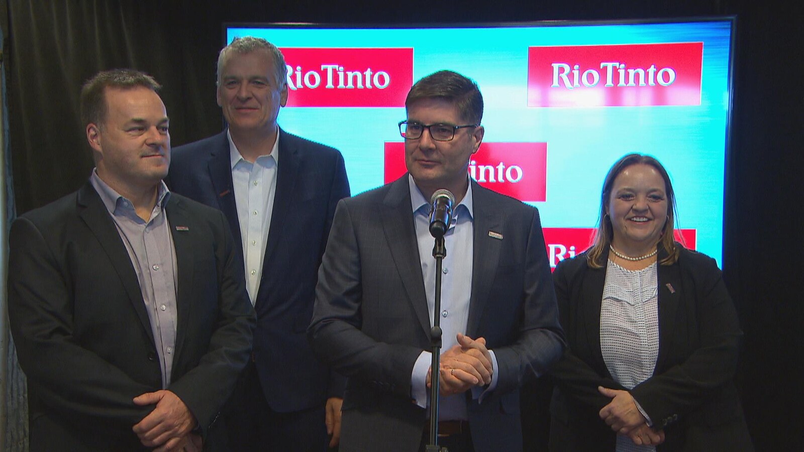 Quatre dirigeants de Rio Tinto répondent aux questions des journalistes devant un micro.