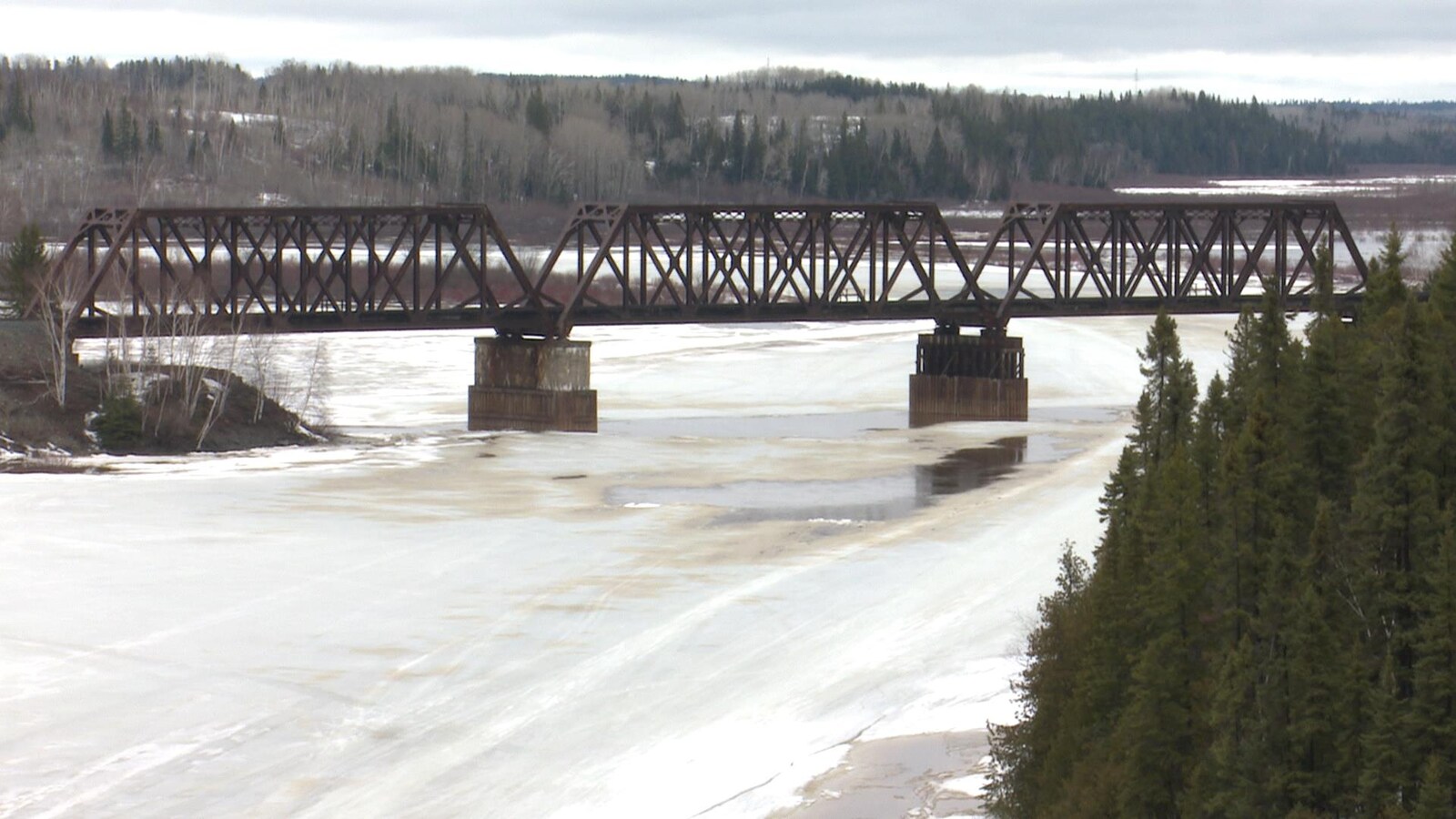 Une rivière traversée par un vieux pont ferroviaire fond au printemps.