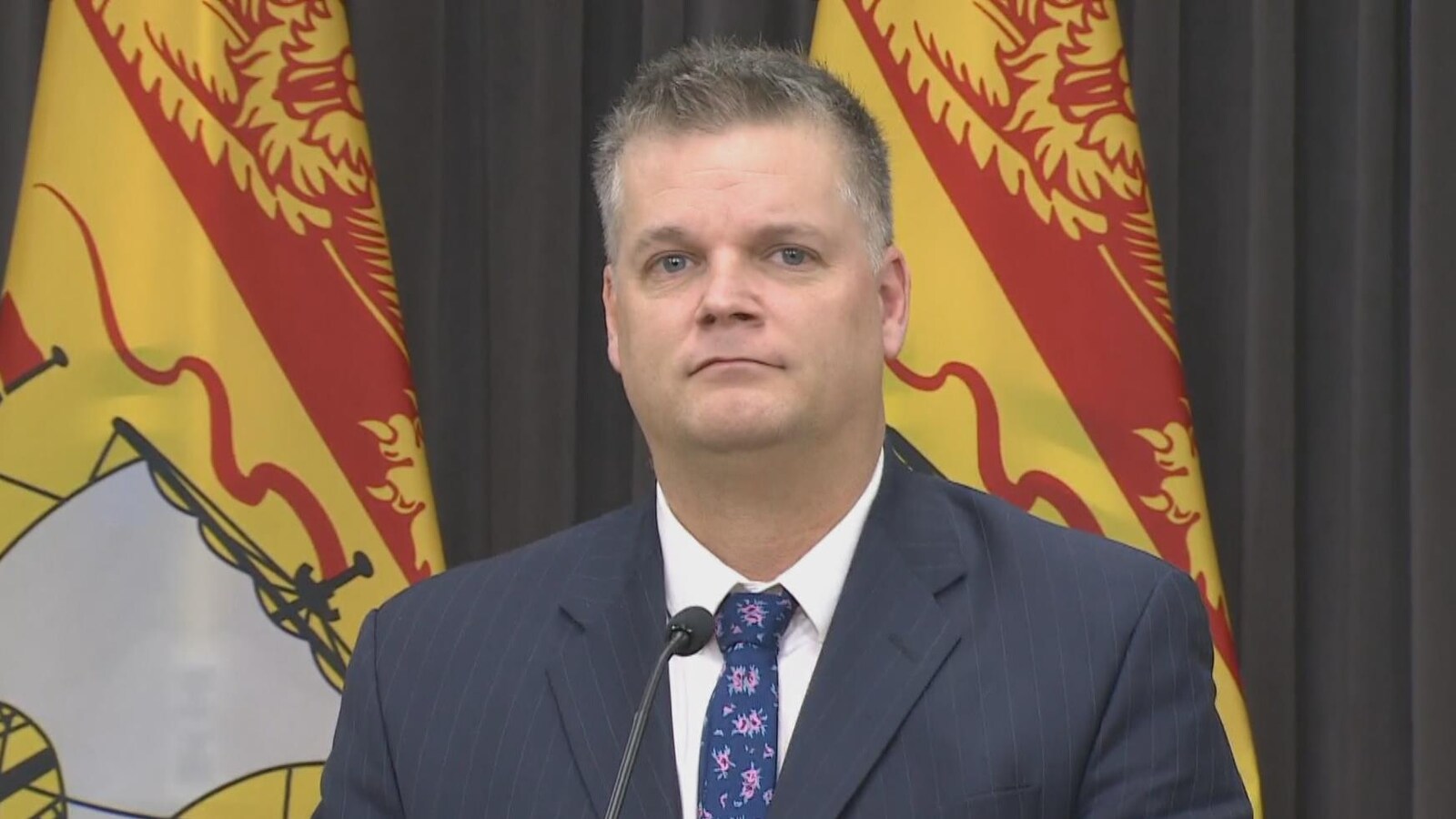 Robert Gauvin, avec des drapeaux du Nouveau-Brunswick en arrière-plan