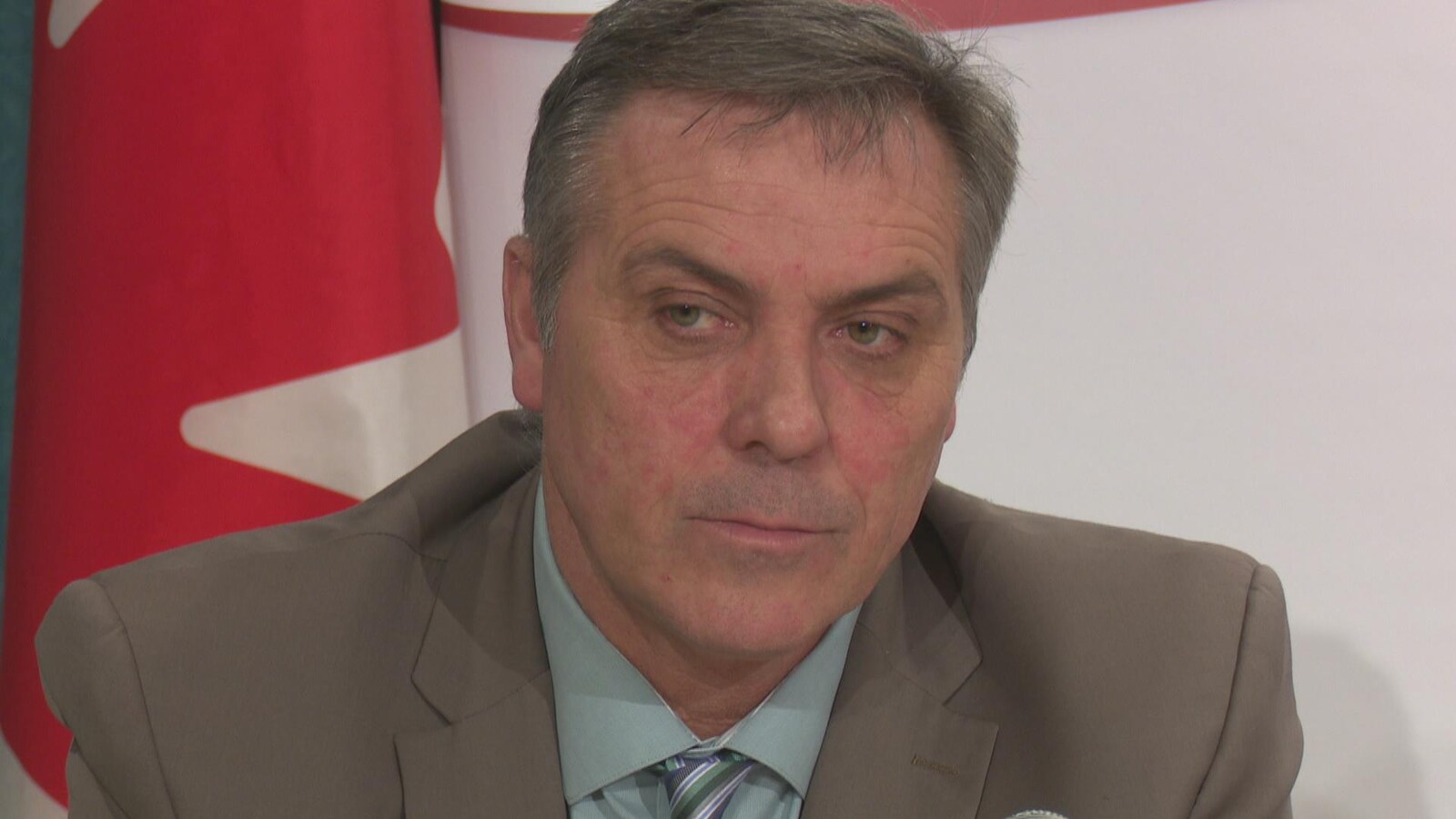 Robert Mitchell devant un drapeau du Canada.