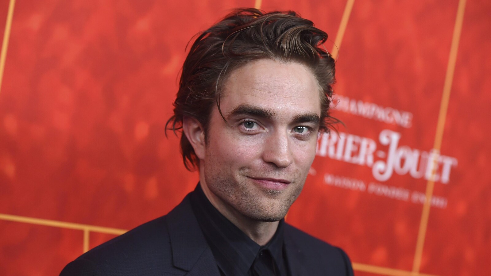 Portrait de Robert Pattinson sur un fond rouge.