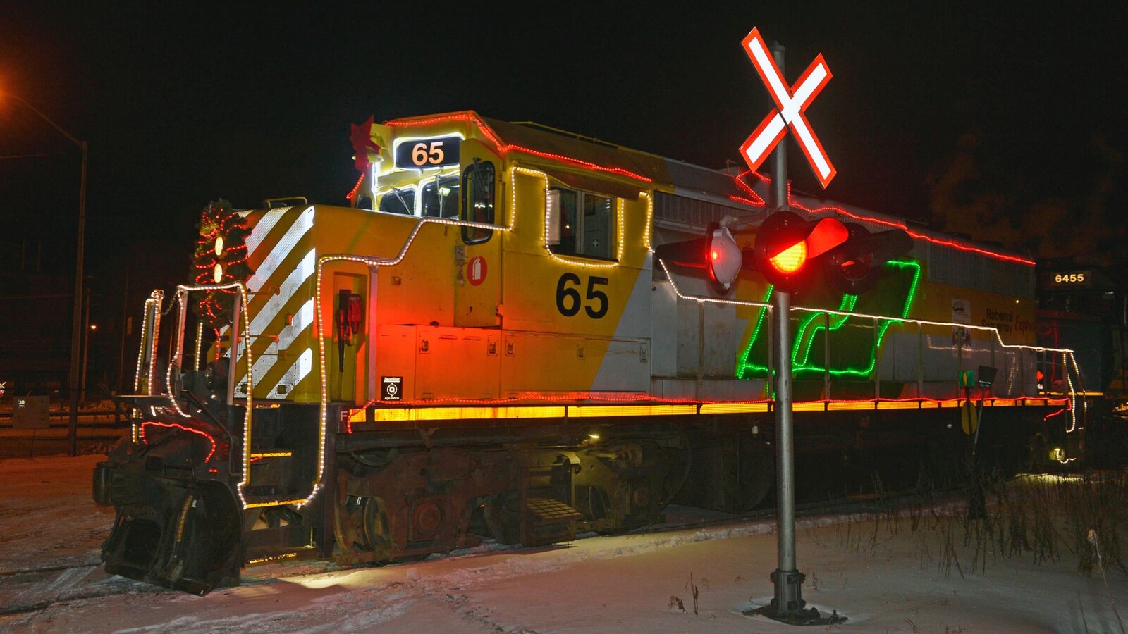 Une locomotive de train décorée avec des lumières et une couronne de Noël circule sur le chemin de fer Roberval-Saguenay.