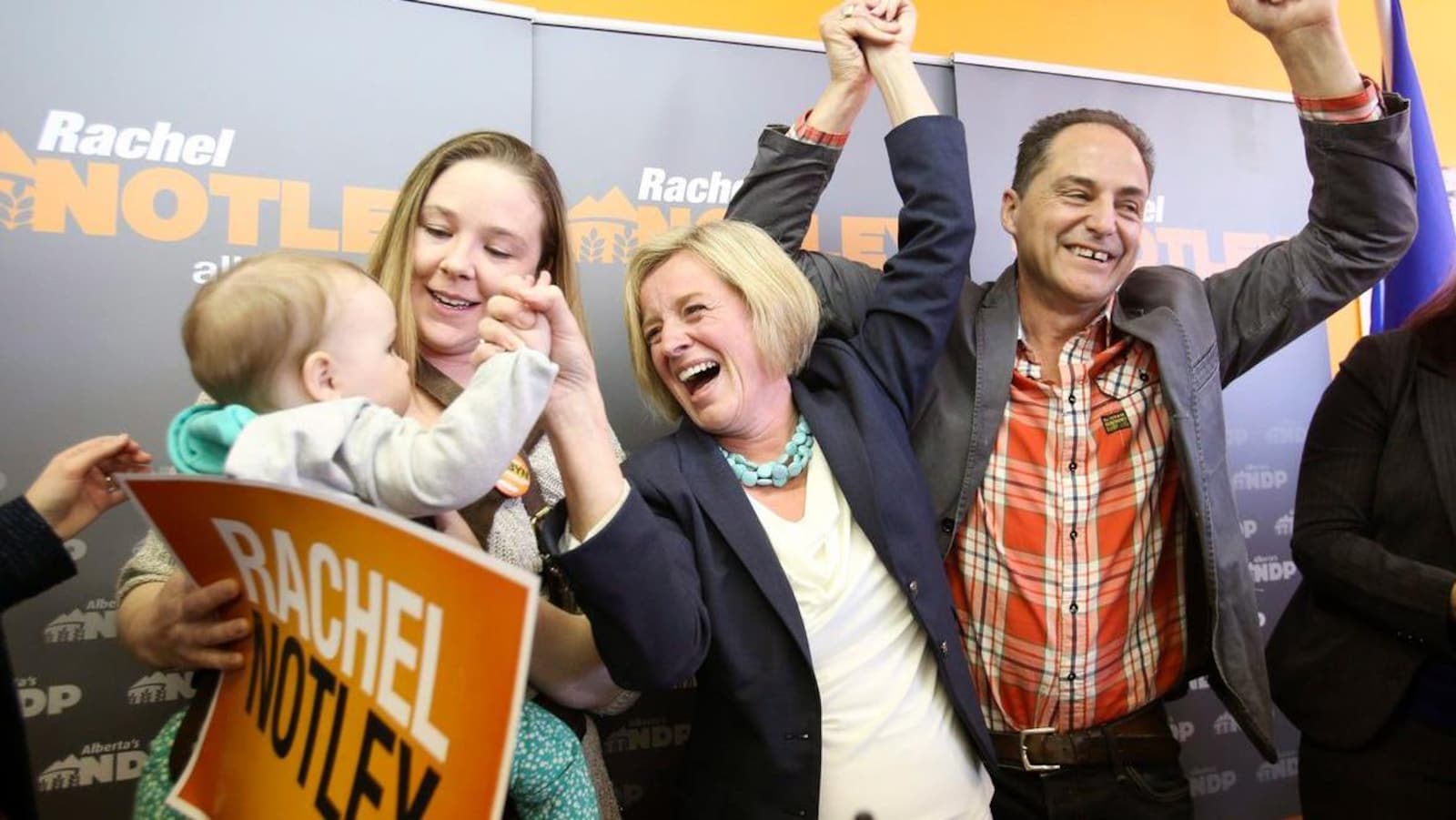 Lors d'un événement de campagne électorale, Robyn Luff tient sa jeune fille que salue Rachel Notley, tout sourire.