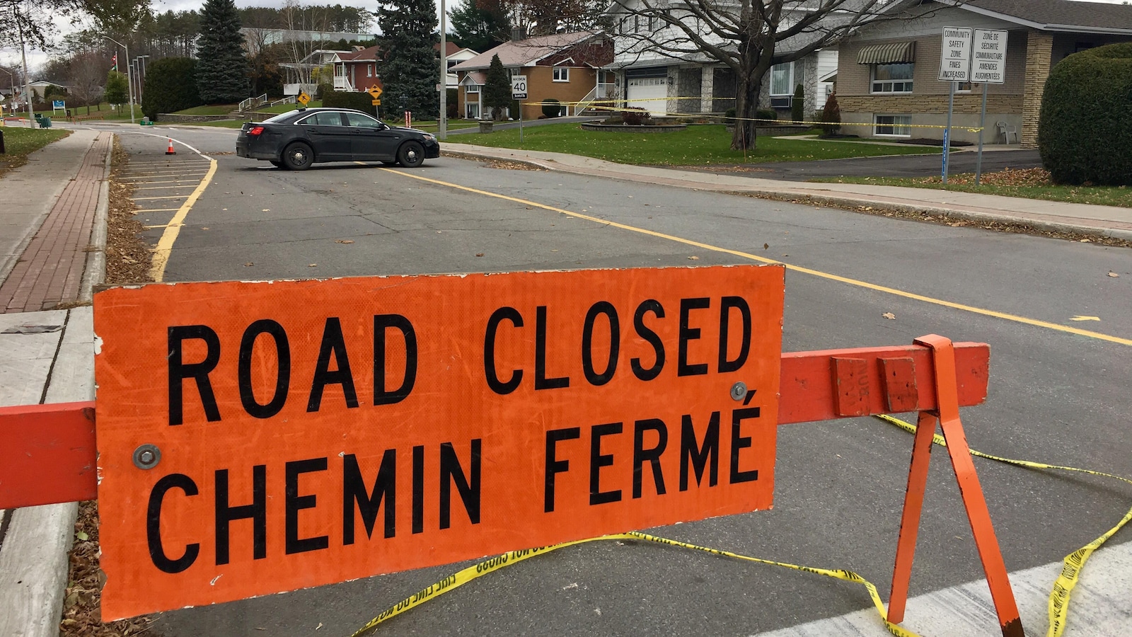 Une pancarte avec la mention «chemin fermé» et une auto-patrouille banalisée bloquent une partie d'une rue.