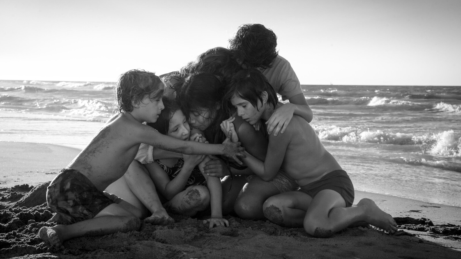 Des enfants blottis les uns contre les autres sur une plage au bord de la mer