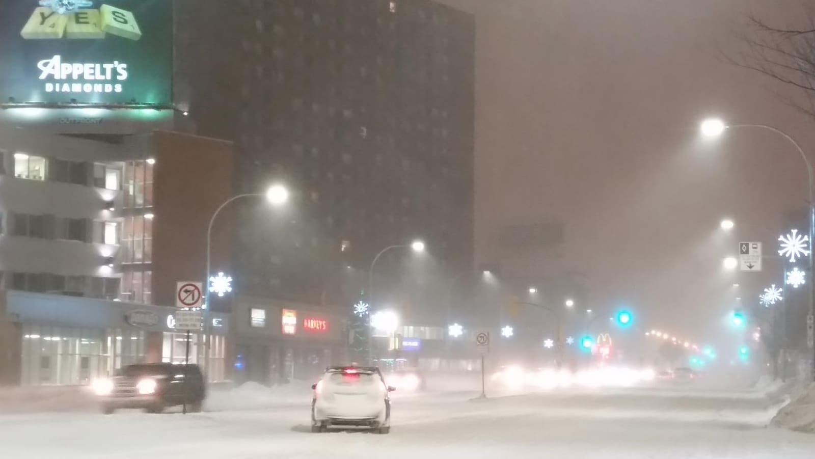 Route enneigée dans le centre-ville de Winnipeg, avec quelques voitures qui circulent.