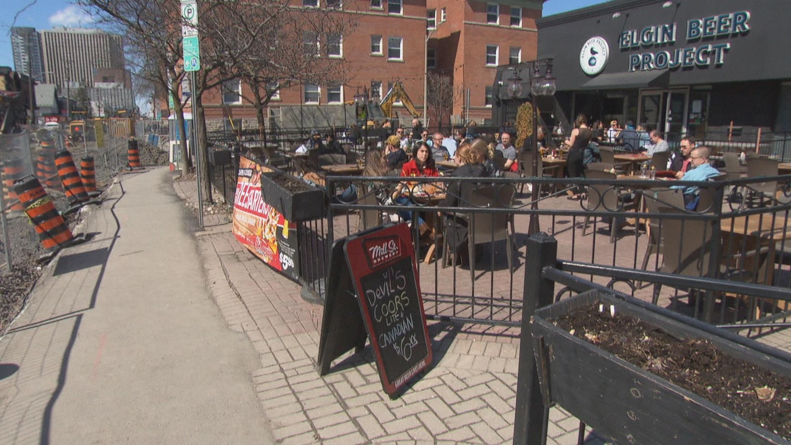 Des gens profitent du beau temps sur la terrasse d'une brasserie.