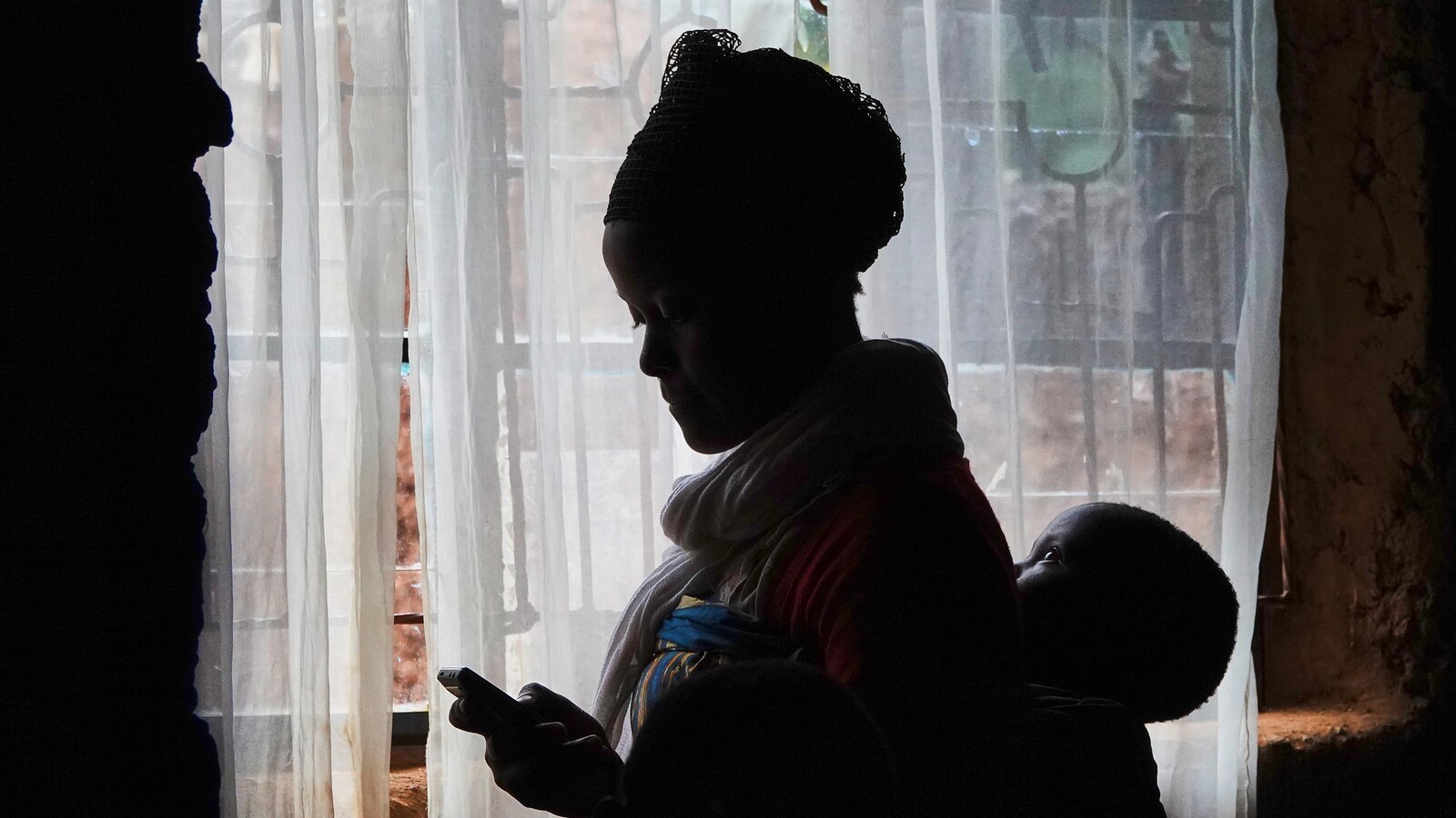 Une jeune mère consulte son téléphone entourée de ses enfants.
