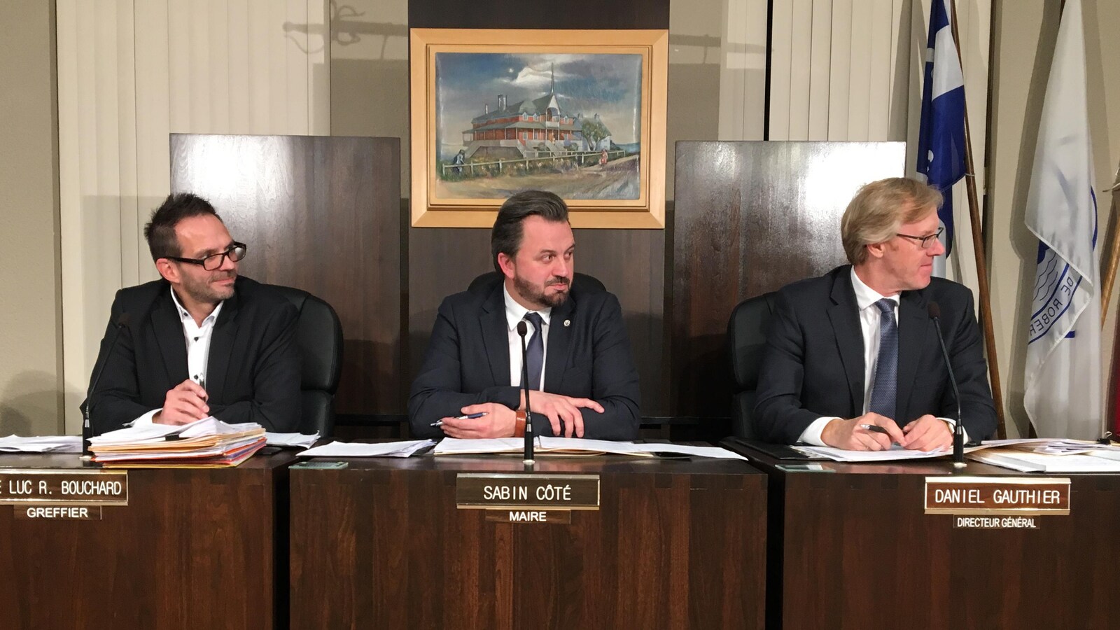 Sabin Côté, entouré du greffier et du directeur général lors d'une séance du conseil municipal.