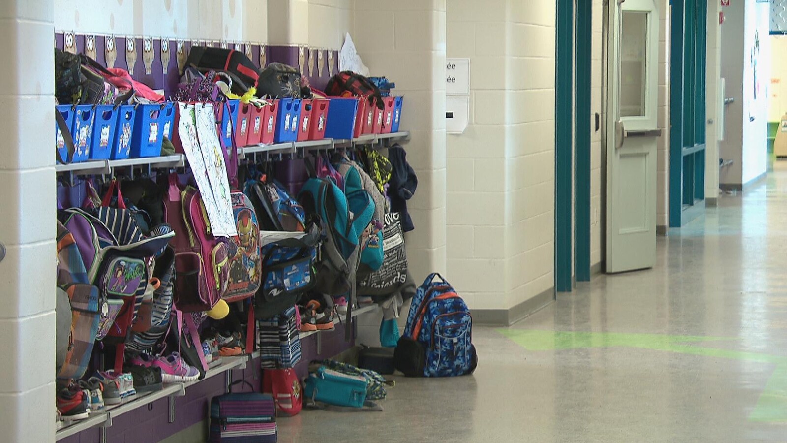Couloir d'école avec des sacs à dos sur des crochets.