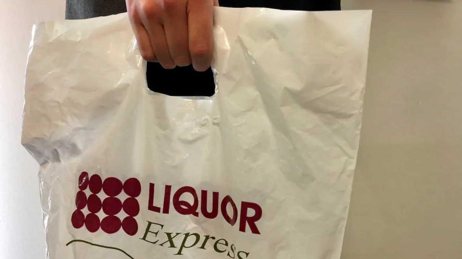 Un homme tient un sac de plastique « Liquor Express ».